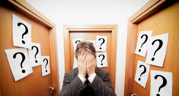 Man with hands over face surrounded by question marks